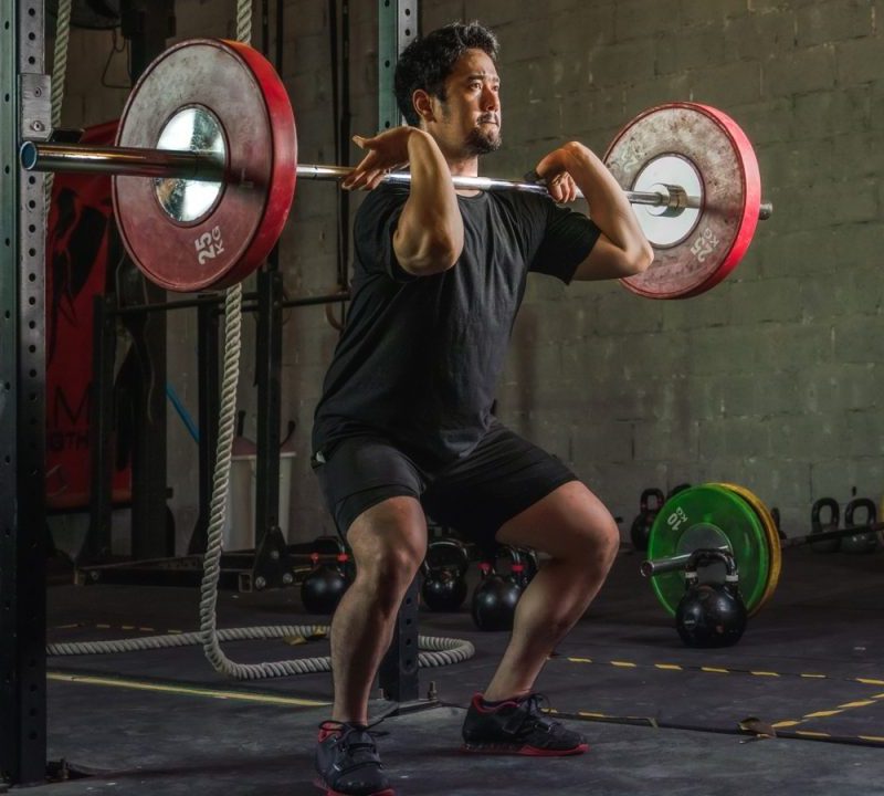A man doing a front squat with a barbell.