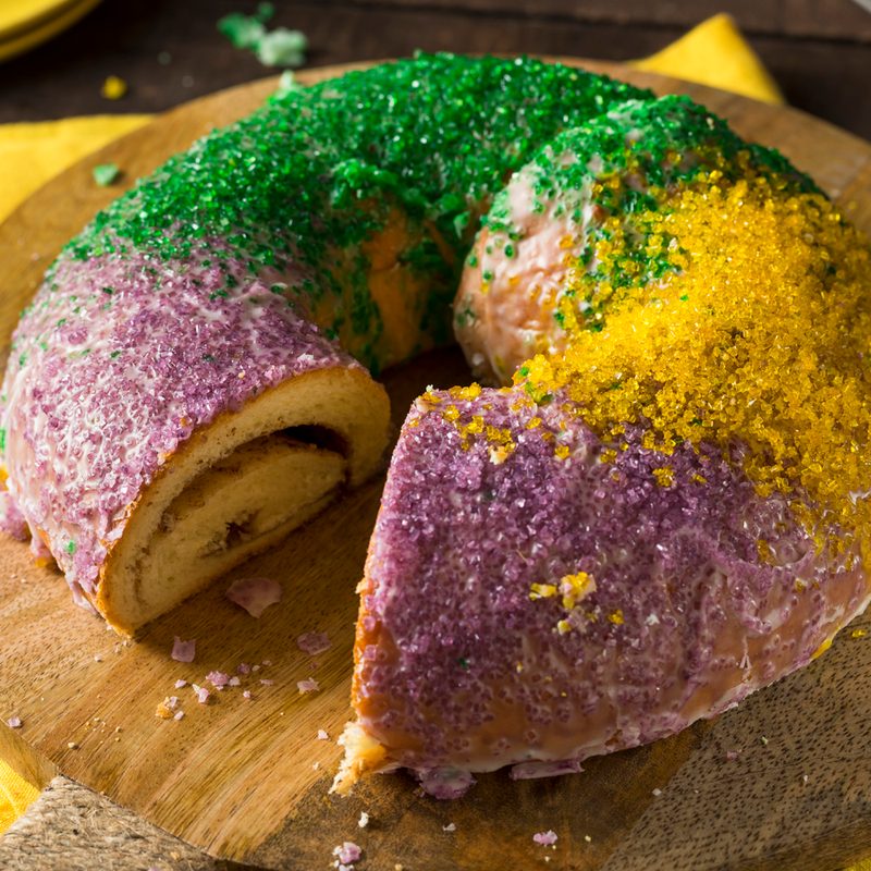 A sliced king cake on a wooden pan.