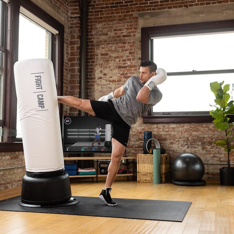Man kicking FightCamp bag in workout.