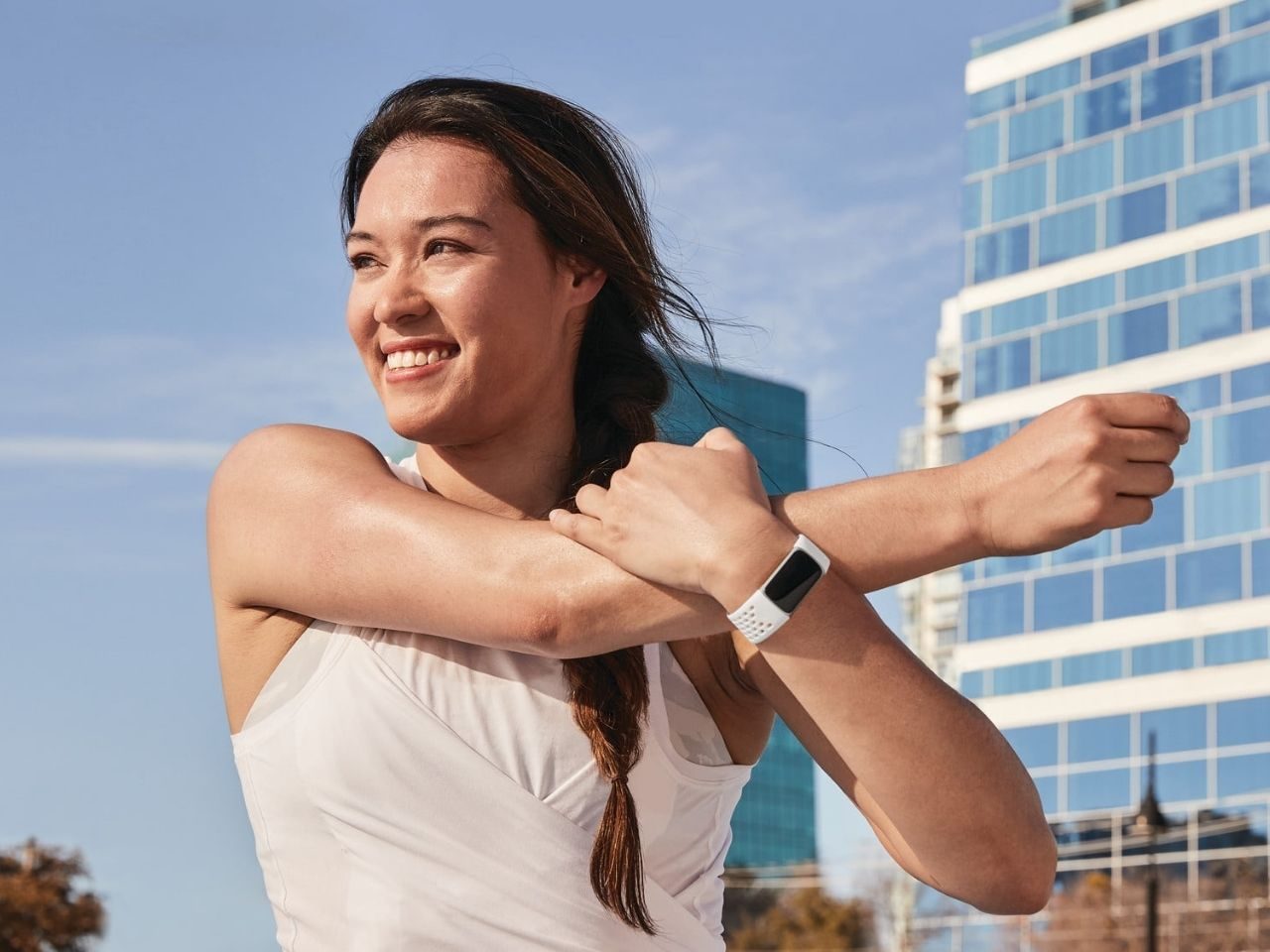 Woman stretching while wearing Fitbit Charge 5.