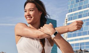 Woman stretching while wearing Fitbit Charge 5.