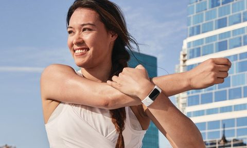 Woman stretching while wearing Fitbit Charge 5.
