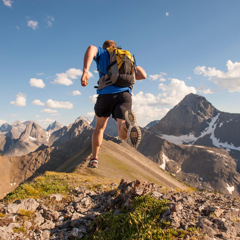 Trail runner in mid air stride, on mountain ridge
