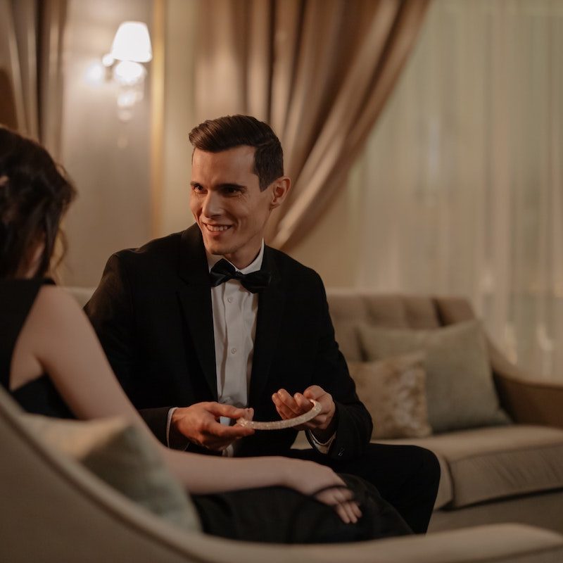 Man in tux giving girlfriend a gift. 
