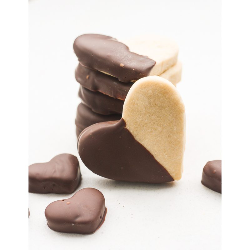 Shortbread cookies shaped like hearts dipped in chocolate.