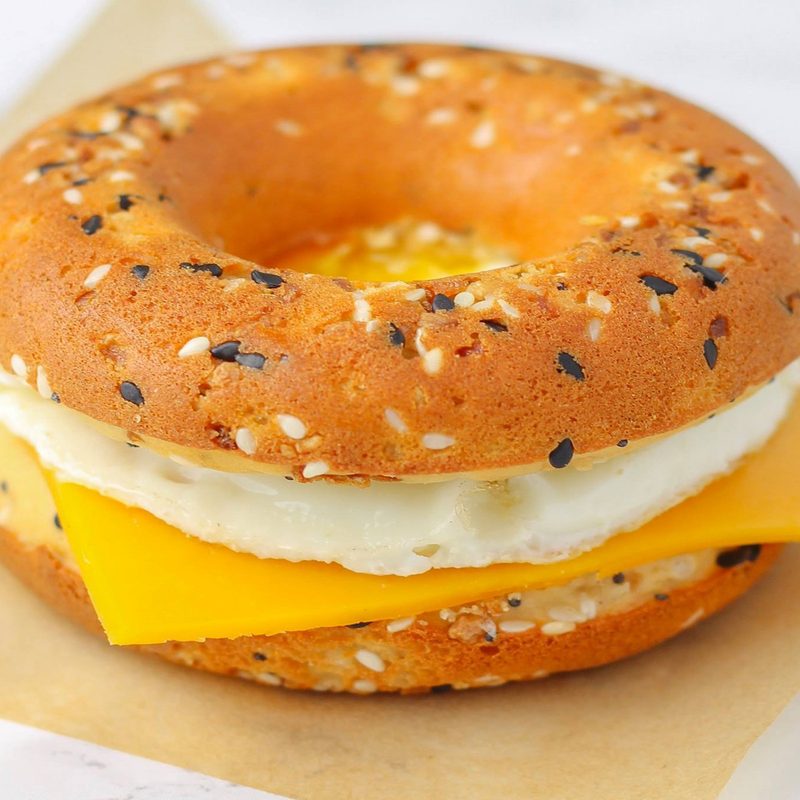 A close-up of a bagel sandwich on brown paper on a table.