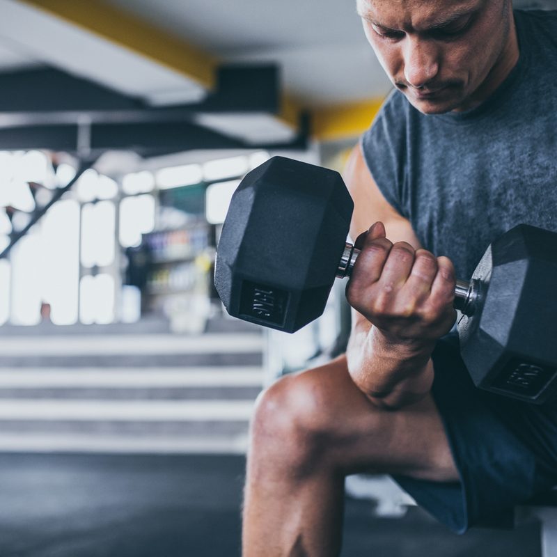A male athlete lifting a dumbbell in a gym