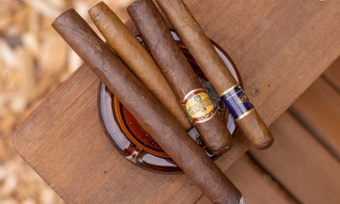 Selection of cigars in an ashtray resting on a wooden table
