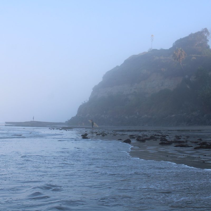 Surfers walk the beach at Swami's Beach in Encinitas, California.