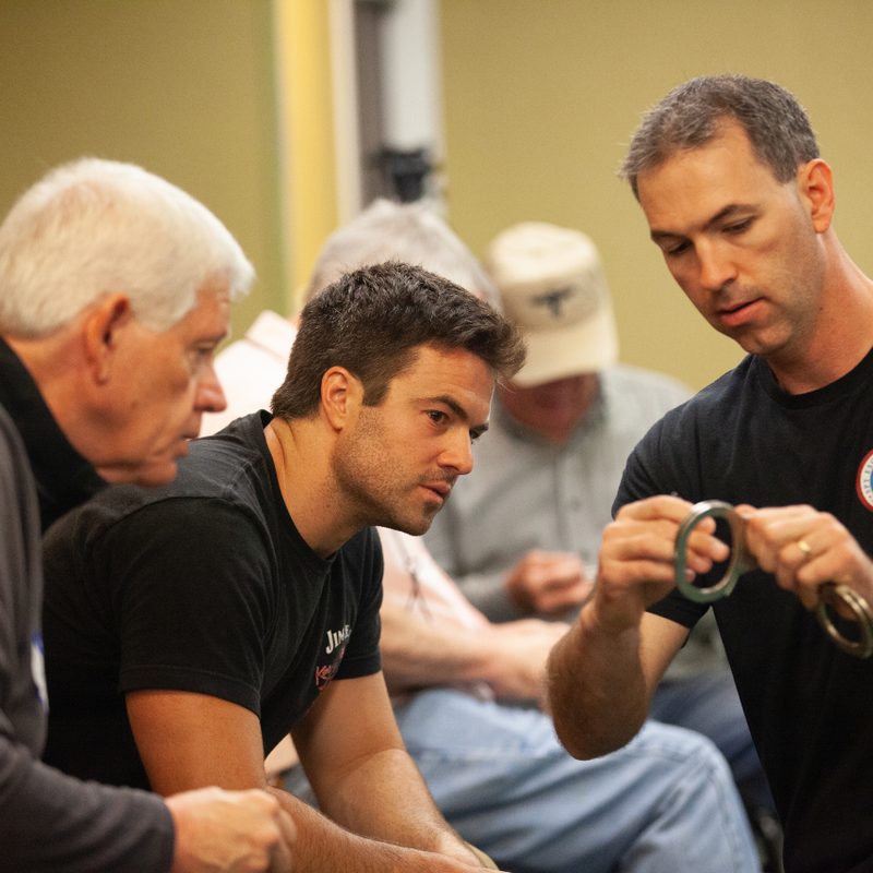 Jason Hanson demonstrating handcuff at Spy Week for two students.