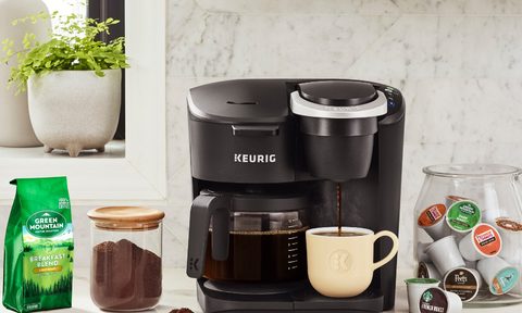 A Keurig K-Duo Essentials single-serve and carafe coffee maker with coffee pods and ground coffee.