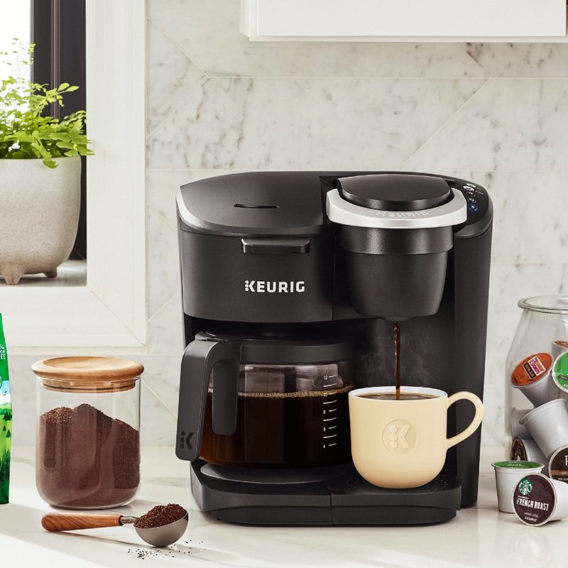 A Keurig K-Duo Essentials single-serve and carafe coffee maker with coffee pods and ground coffee.