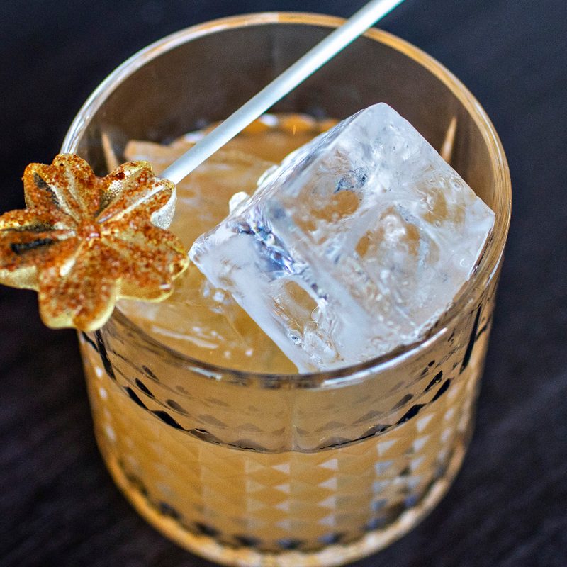 Kinboshi cocktail in glass with one ice cube and Tom Yum lollipop.