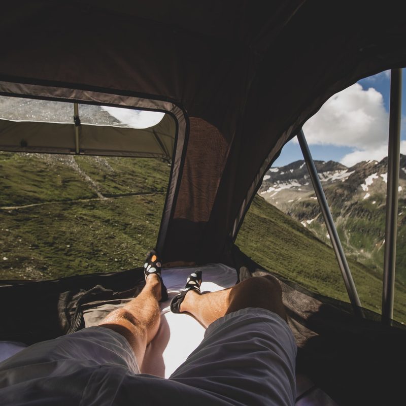 Man solo camping in a rooftop tent in the mountains.