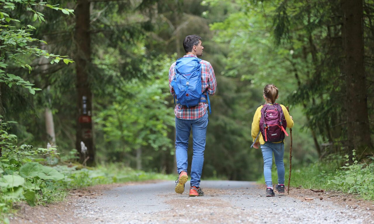 Man hiking on a trail with small girl