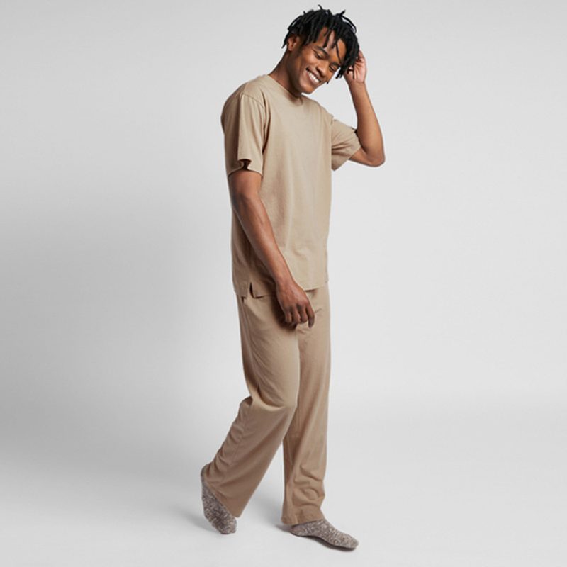 A man posing and wearing a pair of organic cotton pants from Parachute.
