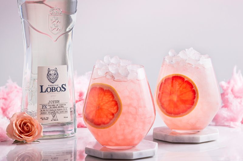 Bottle of Lobos Palma tequila and two glasses with drinks.