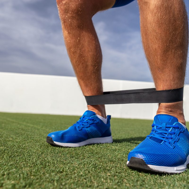 A resistance band around a man's ankles.