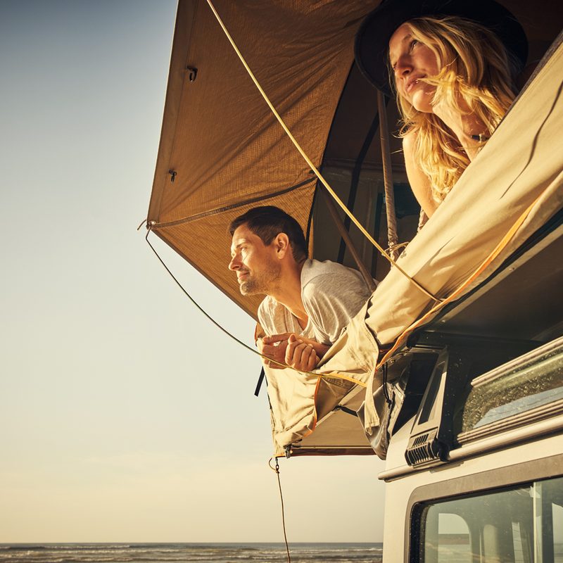 A couple relaxing inside a rooftop tent.