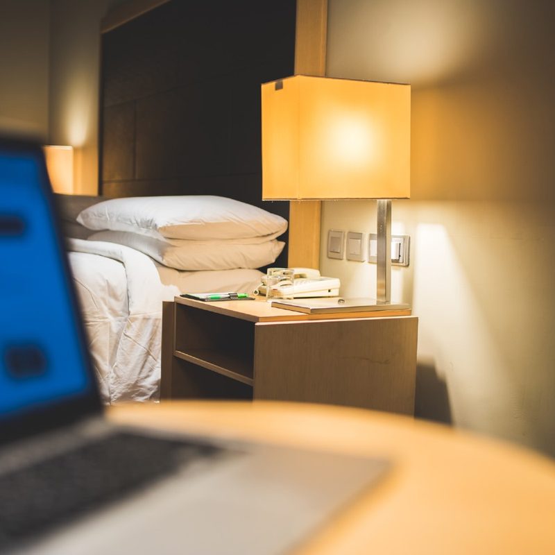 Hotel Room with a Notebook Computer on the Table Near the Bed