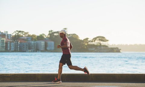 Man running on street by a body of water.