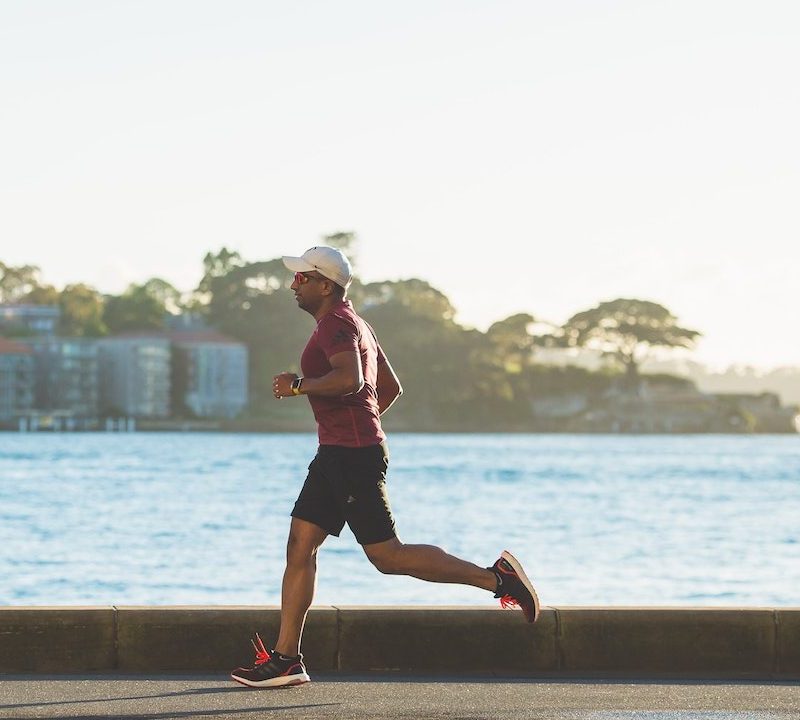Man running on street by a body of water.