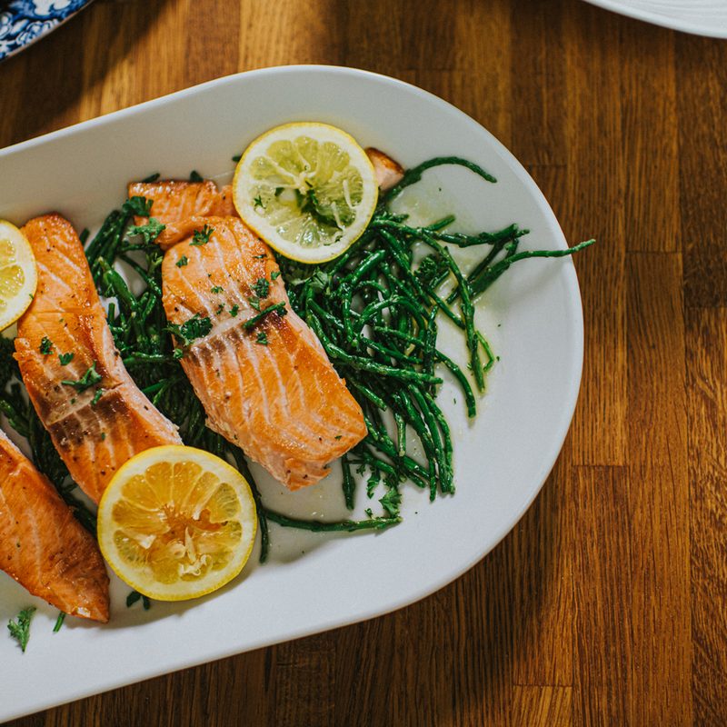 Salmon with vegetables with lemons on an oval plate