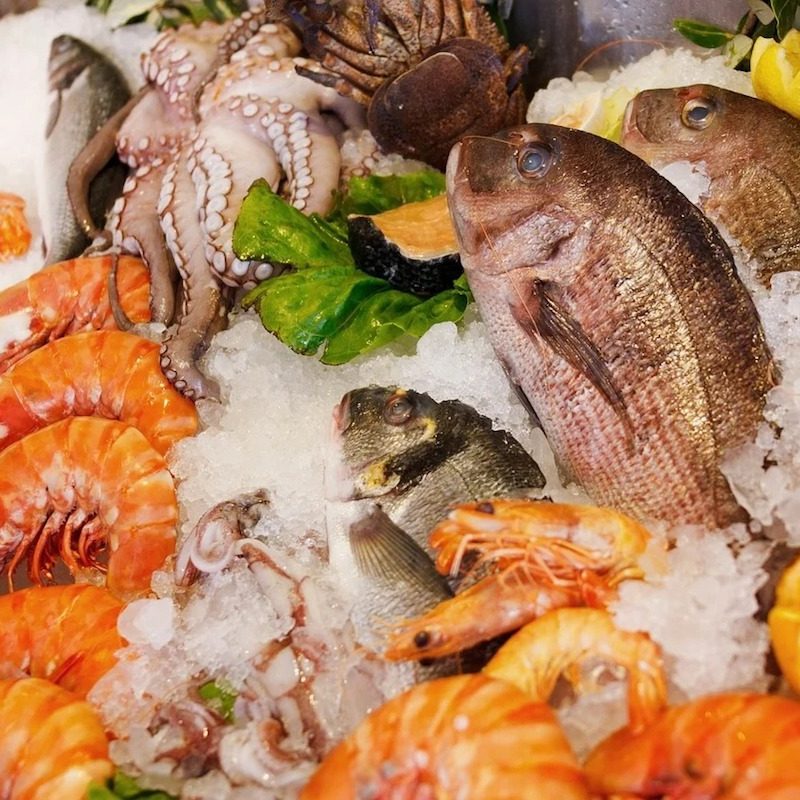 A variety of seafood including prawns, octopus, and fish displayed on ice