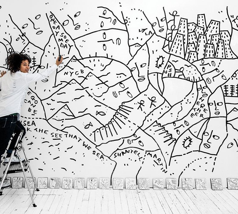 Shantell Martin on a ladder holding a pen to draw her art at NYC Ballet.