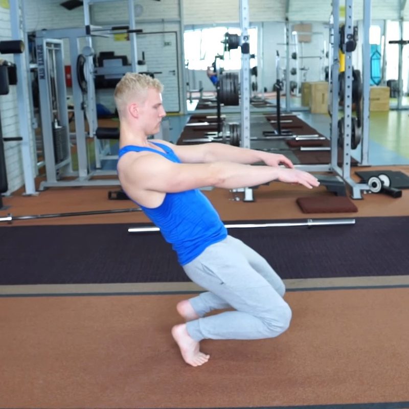 A male athlete doing a sissy squat in a gym.