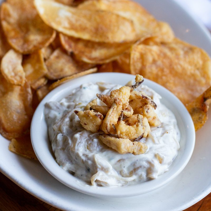 White bowl of Adele's Nashville onion dip with potato chips.