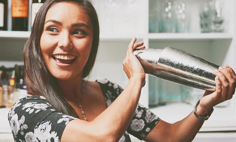 Kira Webster smiling and shaking a cocktail.