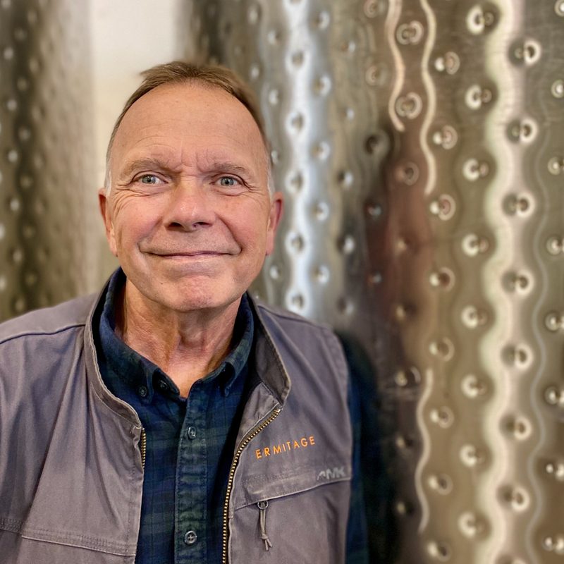 Wayne Bailey next to wine tanks.