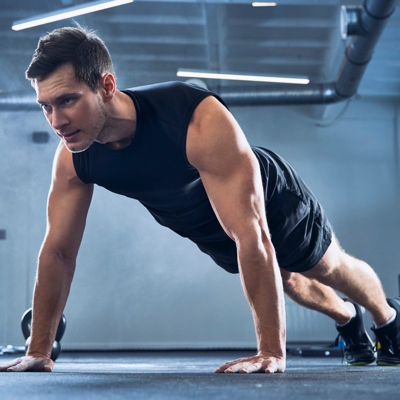 A man doing push-ups in a gym.