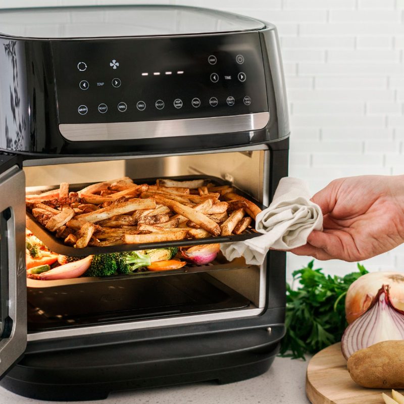 12.6-quart Bella Pro Series digital air fryer oven being opened with french fries on the top shelf and vegetables on the bottom.