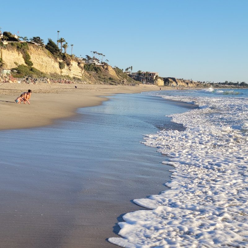 A child and a parent play at the beach in San Clemente, California.