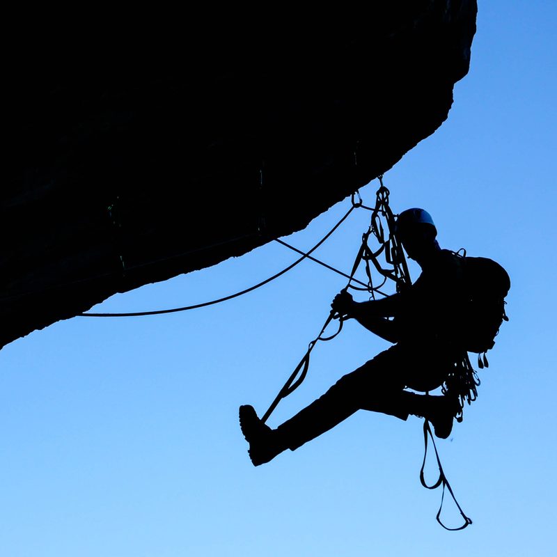 A silhouette of a person aid climbing a rock formation.
