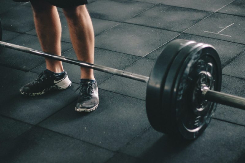 Man standing over a barbell in a gym.