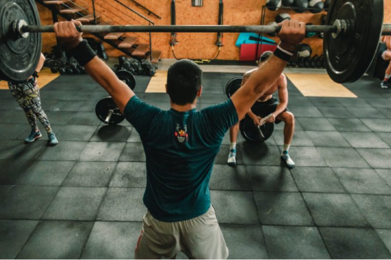 Man working out doing a barbell snatch.
