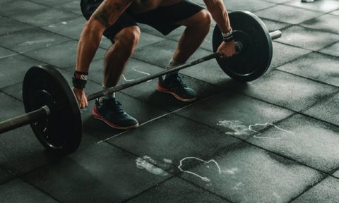 Guy in a gym performing a barbell snatch.