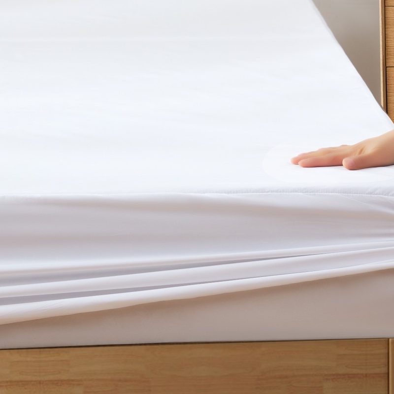Someone places a white fitted sheet onto a mattress
