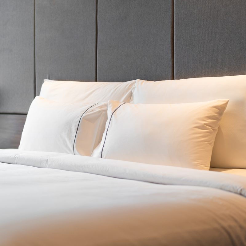 Four white pillows propped up on a bed in a room