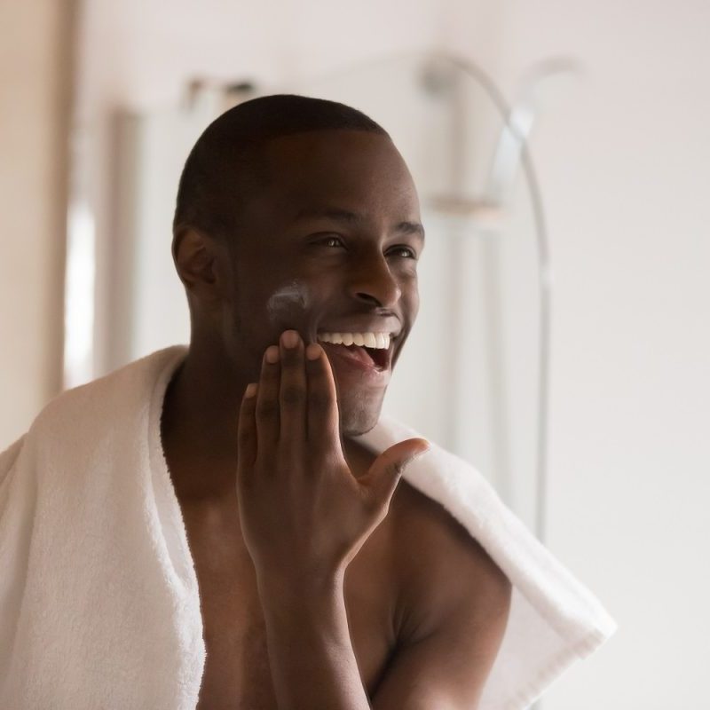 Man putting on face moisturizer.