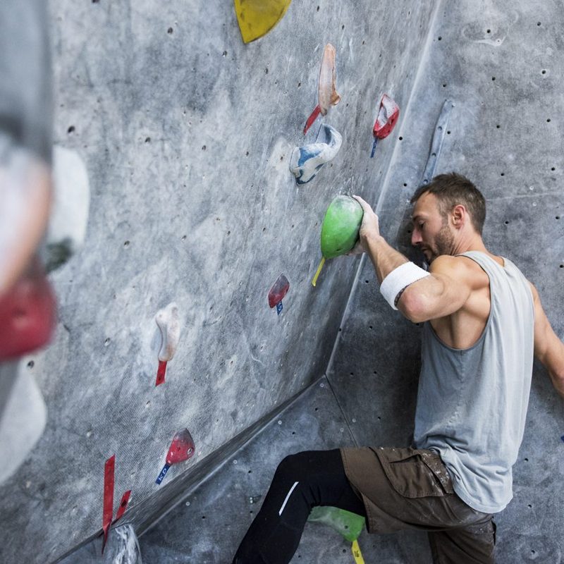 An athletic man climbing on an artificial rock wall.