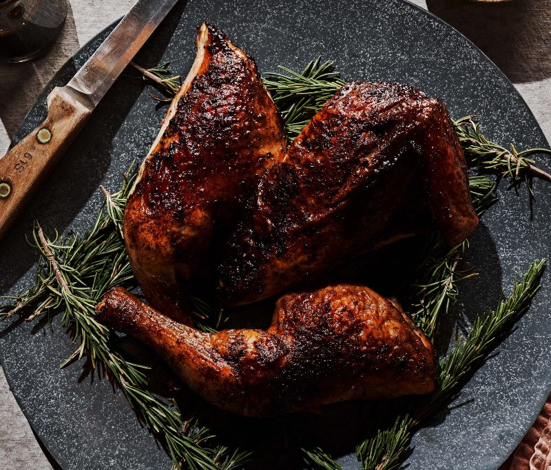 Burn Barrel Chicken on a dark plate with knife.