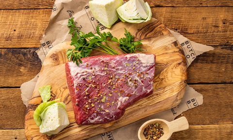 ButcherBox corned beef brisket with aromatics on wooden board.