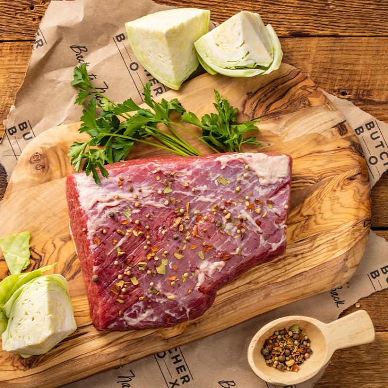 ButcherBox corned beef brisket with aromatics on wooden board.