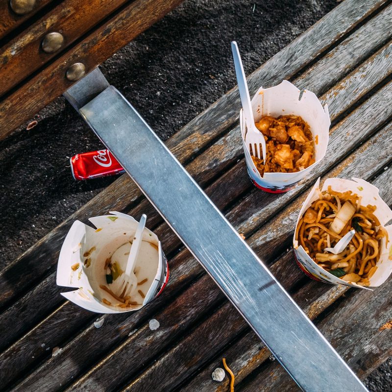 Chinese food leftovers on a wooden bench.
