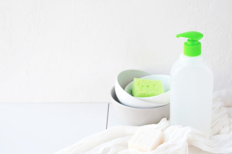Clean bowls, eco dishwashing liquid, towel and soap on white background