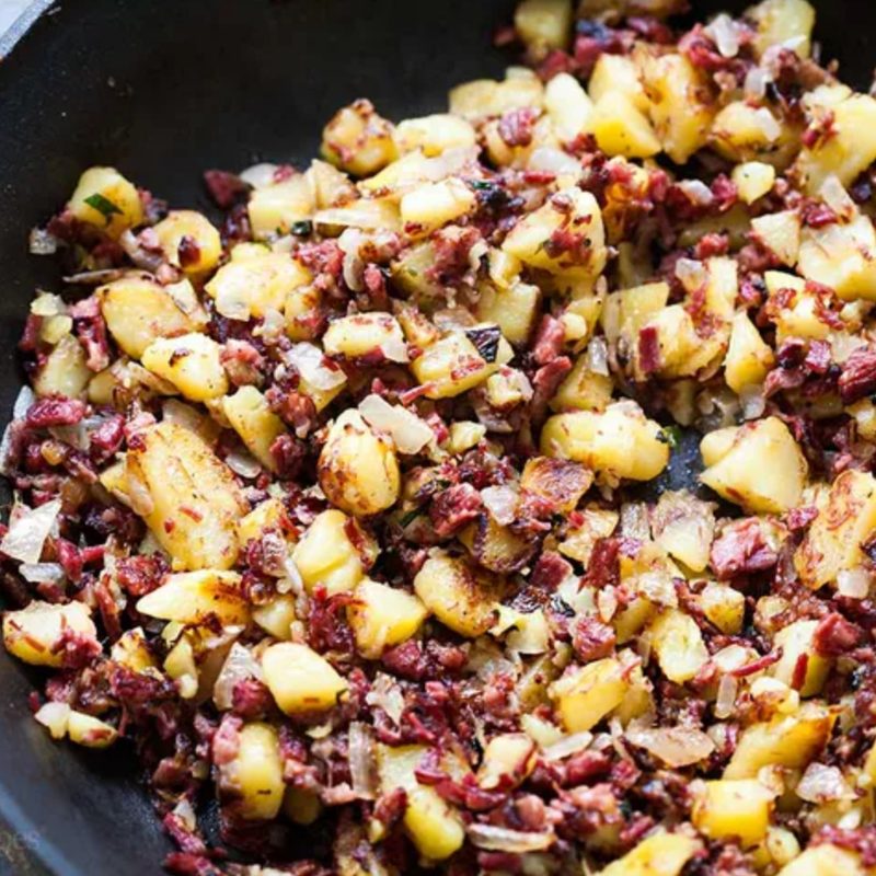 Corned beef hash in a black skillet.